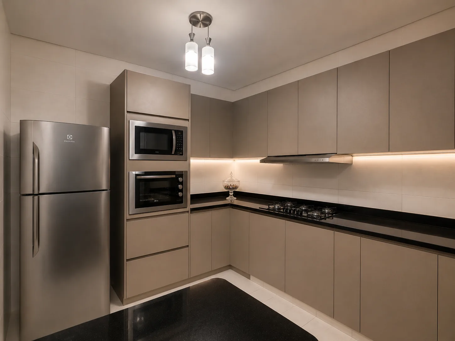 Cozinha planejada em L com marcenaria fendi, torre de fornos e iluminação embutida